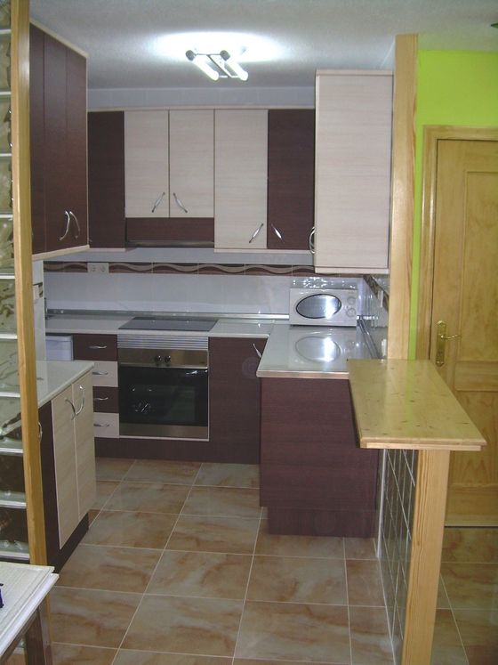 A kitchen with a dark wood breakfast bar